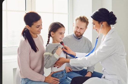 Mother, father, and daughter smiling during a checkup with their doctor